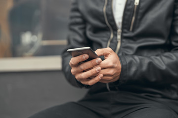 Close-up. The guy is holding a smartphone in his hands. Prints on the smartphone. On the street