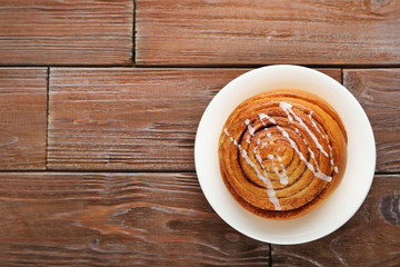 Cinnamon bun in plate on wooden table