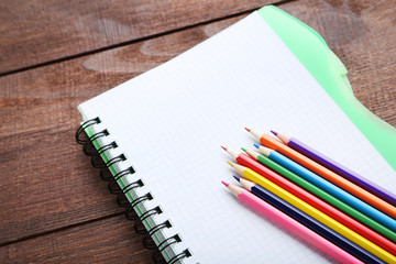 Drawing colourful pencils with notebook on brown wooden table