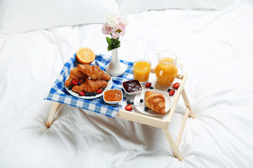 Fototapeta na wymiar Tasty breakfast in bed on wooden tray