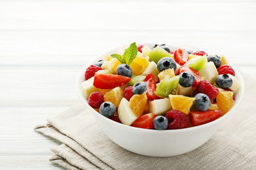 Fresh fruit salad in bowl on white wooden table