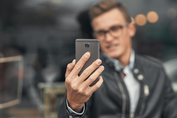 Close-up. A cute guy does selfie on a smartphone. On the street