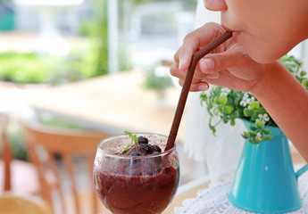 Close-up female drinking a blueberry smoothie in the cafe.