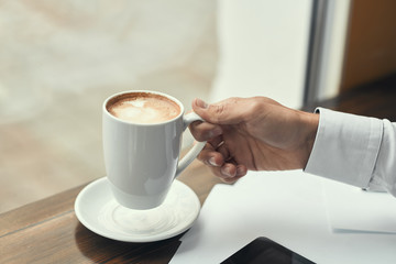 A guy in a white shirt, drinking coffee.