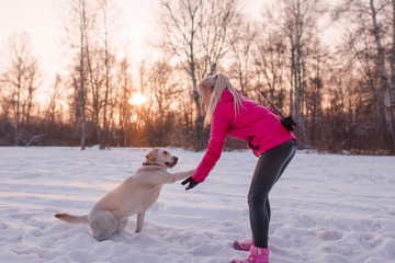Labrador dog gives girl blonde paw winter