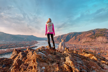 Fototapeta premium the girl with the dog looking into the distance in the spring in cold
