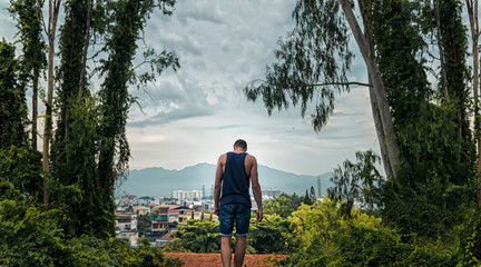 the guy in the shirt in a forest on the background of the city