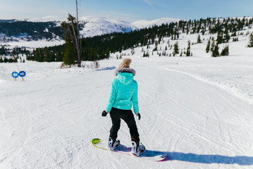 the girl in blue going down a hill on a snowboard