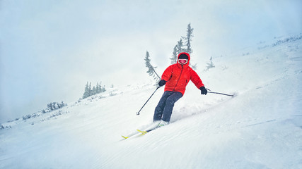 the guy in the red ski rides from the mountain in a storm