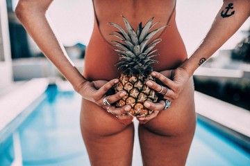 Close-up of women holding pineapple behind her back