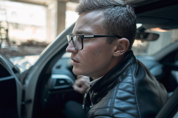 Close-up. Young handsome man looks out of a white car