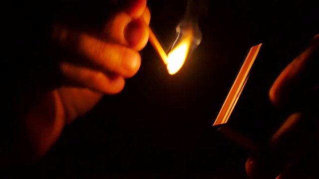 How to Strike a Match. Slow Motion. Man lights up and holds the burning mach stick  with the matchbox in darkness. Recorded at 96 fps, Running at 25fps