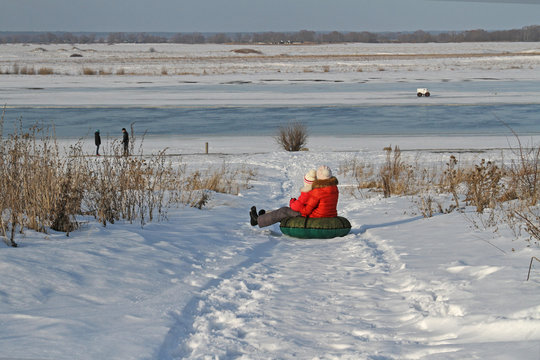 Mother and child sliding down on snow tubing in a winter landscape