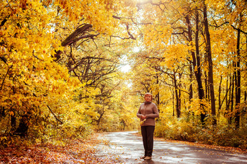 Middle-aged woman walks in autumn forest