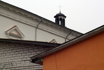 Fototapeta na wymiar Catholic church roof top with cross behind residential buildings.