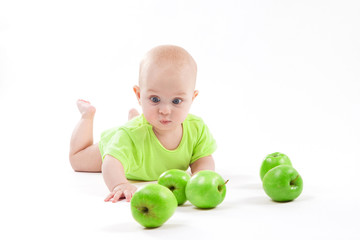 Fototapeta na wymiar cute surprised baby looks at green apple on a white background