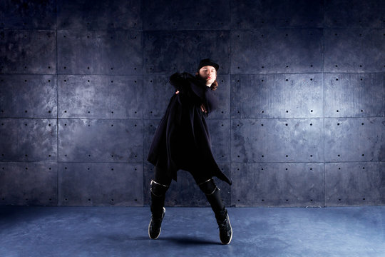 Male / man hip hop / r&b / break dancer dancing wearing in black stylish modern cloth on industrial black background