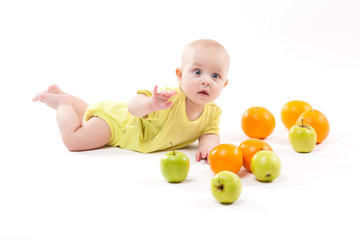 Fototapeta na wymiar cute smiling healthy child lies on a white background among fruit