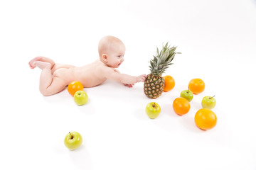 naked child on a white background surrounded by exotic fruits