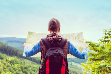 Woman traveler with backpack checks map to find directions in wilderness area, real explorer....