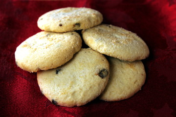 Group of five choc chip and fruit cookies, on a festive red background.