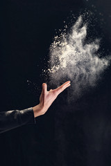 Obraz na płótnie Canvas Man hands throw white powder on dark background