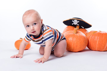 Beautiful baby in a striped shirt on a white background pumpkins