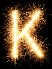 Sparkler firework light alphabet K isolated on black