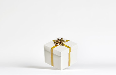 White cube gift box with golden stripes and bow floating in white background