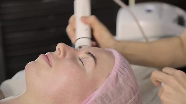 Beautician does rf face lifting procedure for a woman in a beauty saloon. Hardware cosmetology