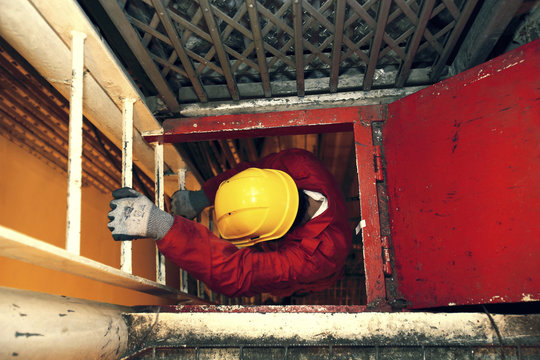 Workman climbing down a ladder.