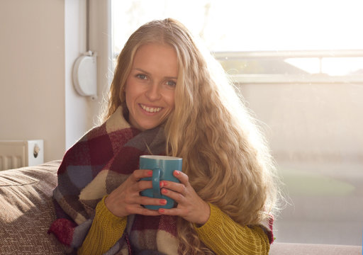Girl drinking tea on sofa in winter time