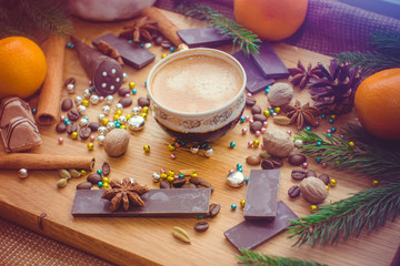 Hot coffee and christmas decorations . Cup of coffee and chocolate on wooden table. Christmas decorations on a kitchen, gifts and food on a wooden background. Magic moments in everyday life