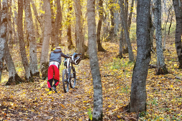 Naklejka premium A young guy rolls his bike up the hill