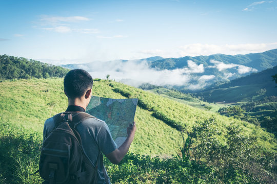 Young Man Traveler With Map Backpack Relaxing Outdoor With Rocky Mountains On Background Summer Vacations And Lifestyle Hiking Concept