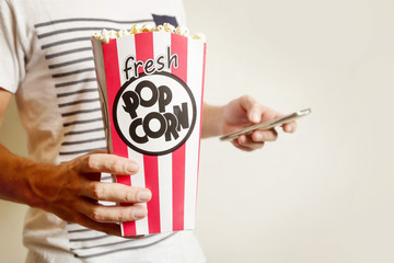 Man holding cell phone and box of fresh popcorn