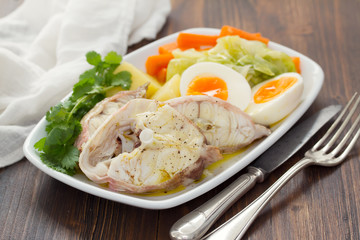 boiled fish with boiled potato, carrot, cabbage and egg on white plate