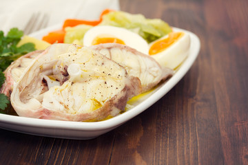 boiled fish with boiled vegetables and egg on white plate