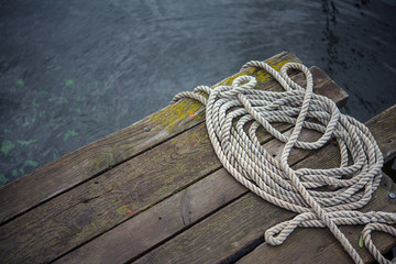 Old ship rope on a wooden obsolete pier