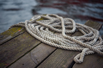 Fototapeta na wymiar Old ship rope on a wooden obsolete pier