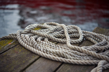Fototapeta na wymiar Old ship rope on a wooden obsolete pier