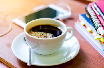 Cup of dark coffee  with smart phone and book on  wooden background. Coffee can help in your education time.