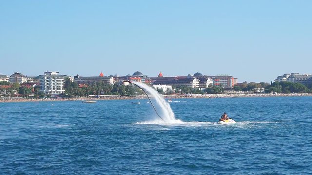 Turkey, October 12, 2017. Shot of flyboard boots in action a few meters over the water. Man fights to find balance and falls. Slow motion.