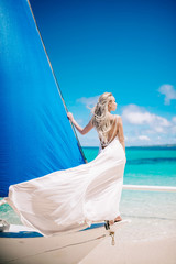 beautiful bride on wedding day ready for travel by sail boat.