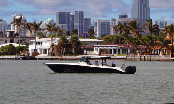 Black and white sport fishing boat idling off DiLido Island in Miami Beach with Miami tall building skyline in the background.