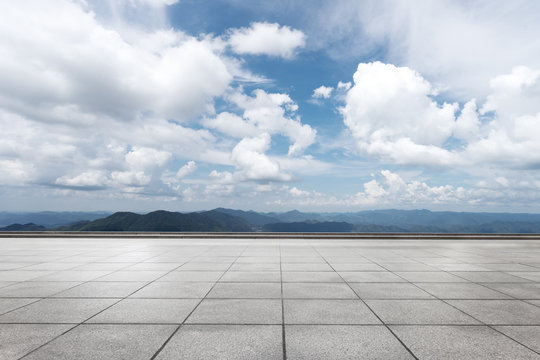 empty marble floor with green hill in cloud sky