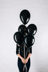 woman holding black balloons