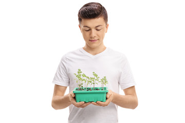 Teenage boy looking at a plant in a pot