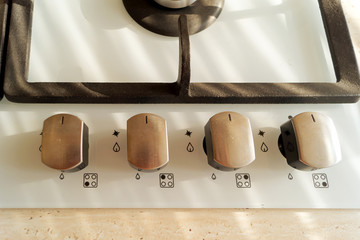 Four metal handles of gas cooker panel, top view.