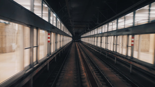 Fototapeta View of subway tunnel as seen from the rear window of moving train. Fast underground train departs from modern subway station.